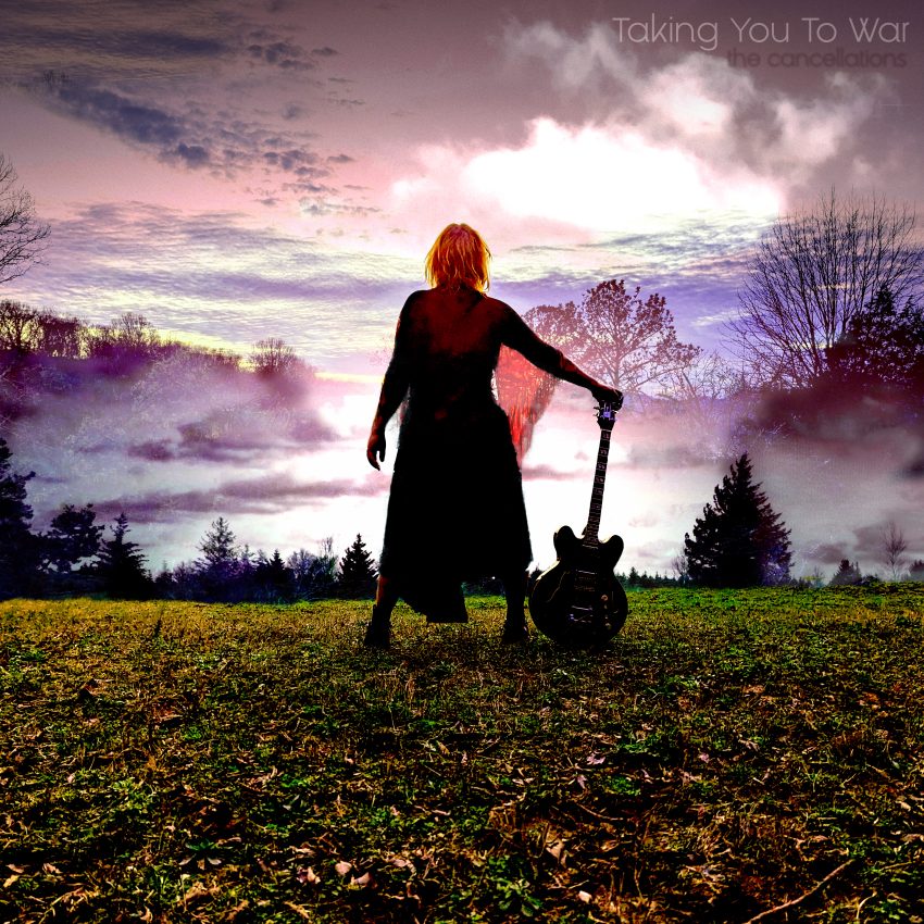 A woman stands with her back to the camera, holding the headstock of a guitar that rests on the ground. She is in a large field and the sky in front of her is cloudy, dotted with mountains and trees.